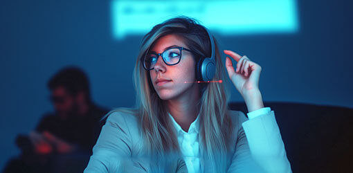 Woman listening to a Executive In-Studio Webinar. She is wearing headphones.